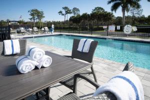 迈尔斯堡Holiday Inn Express & Suites - Fort Myers Airport, an IHG Hotel的游泳池旁的桌椅