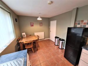 考文垂3 Bedroom Apartment Coventry - Hosted by Coventry Accommodation的厨房配有木桌和黑冰箱。
