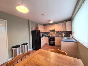 考文垂3 Bedroom Apartment Coventry - Hosted by Coventry Accommodation的厨房配有木桌和黑冰箱。