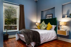 开普敦Obz Hotel的一间卧室配有一张蓝色墙壁的床和一扇窗户