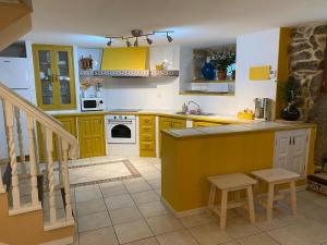 科巴罗Casa Rualeira的厨房配有黄色橱柜和带凳子的柜台。