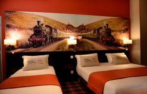 里昂维多利亚里昂佩拉什酒店的两张床铺,位于酒店客房,配有火车壁画