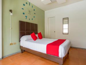 奇瓦瓦Hotel Allende 104的一间卧室配有一张带红色枕头的床和时钟