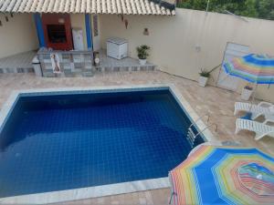 拉巴拉德纳圣米格尔Casa na Barra de São Miguel的一座房子旁带两把遮阳伞的游泳池