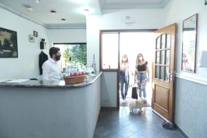 阿蒂巴亚Pousada Vista da Pedra Atibaia的男人和两个女人和狗一起站在柜台上