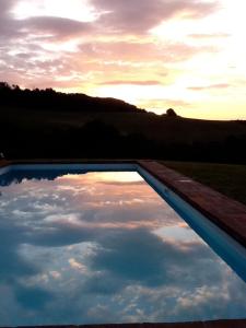 Monte San PietroCa' Lo Spicchio的日落时分在游泳池中反射天空