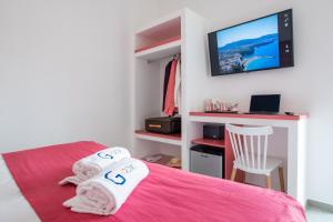 圣安吉洛Al Campanile的卧室配有粉红色的床,墙上配有电视