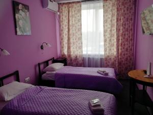 梁赞Sleep House Рязань的紫色的客房设有两张床和一扇窗户。