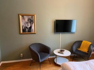 卡尔斯克鲁纳第一斯达特酒店的一间设有两把椅子和一台墙上的电视的房间