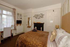斯沃尼奇罗伯茨布鲁克旅馆的一间卧室配有一张床、一张桌子和一个壁炉