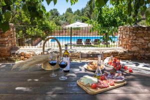 UserasMas de les Garroferes的池畔餐桌旁摆放着葡萄酒和食物