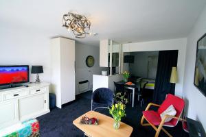 霍勒姆LUXE Appartement ZEEDUIN, Bgg, eigen Terras - volledige KEUKEN- Resort Amelander Kaap, Incl verwarmd Hotel-ZWEMBAD的带电视的客厅和带桌子的房间。