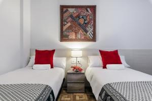 圣塞瓦斯蒂安Zurriola Surf的客房内的两张床和红色枕头