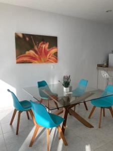 莫雷洛斯港Hermosa Casa Vacacional Puerto Morelos的一间设有玻璃桌和蓝色椅子的用餐室