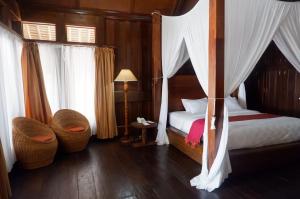 万慈Wakatobi Patuno Diving and Beach Resort by SAHID的一间卧室配有天蓬床和藤椅
