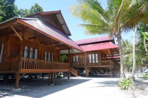 万慈Wakatobi Patuno Diving and Beach Resort by SAHID的海滩上的一座棕榈树建筑