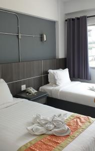 洛坤府The Inka Hotel的酒店客房,配有两张带白色床单的床