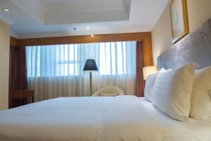 青岛青岛颐中皇冠假日酒店的卧室配有一张大白色床和窗户