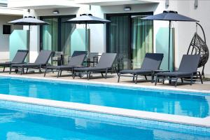 萨索斯Anassa Blue Boutique Hotel的一组椅子和遮阳伞,位于游泳池旁