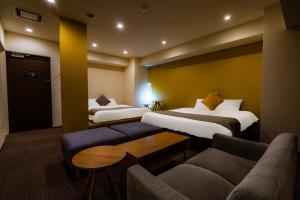 札幌Randor Hotel Sapporo Suites的酒店客房,设有两张床和一张沙发
