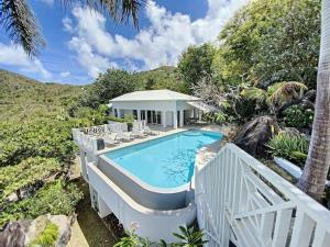 Anse Marcel Villa Casa Sand, luxury, 5 min walk from Anse Marcel beach的一个带椅子的游泳池以及一座房子