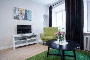 维尔纽斯Baron Old Town Apartments的客厅配有绿色椅子和桌子
