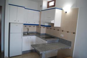 拉雷斯廷加Apartamentos Los Saltos的厨房配有白色橱柜和冰箱。