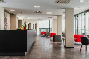 塞格拉泰Fasthotel Linate的一个带红色椅子和柜台的办公大厅