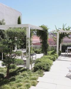 里斯本Destino Lisboa Apartments的花园设有白色椅子和凉亭