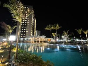萨利诺波利斯Salinas Exclusive Resort的一座游泳池,晚上有一座建筑和棕榈树