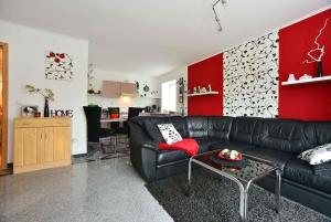 Mölln-Medow吕根岛贝尔根1号公寓的客厅配有黑色真皮沙发和红色墙壁