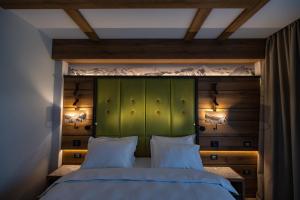 锡纳亚Hotel Belmont的一间卧室配有绿色床头板和两个白色枕头