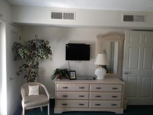 大洋城比斯坎套房酒店的一间卧室配有梳妆台、电视和椅子