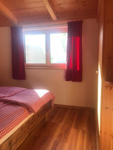 Neumarkt in SteiermarkApartment Wohlesser的一间卧室配有床和红色窗帘的窗户