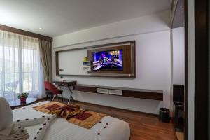 瓦亚纳德Saugandhika West Gate的酒店客房设有一张床和墙上的电视