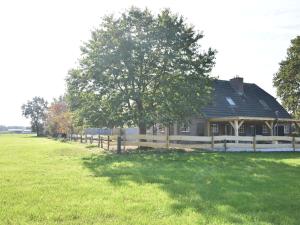 霍尔滕Beautiful holiday farm in Holten的田野中带栅栏和树的房子