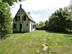 奥德多普Quintessential holiday home in Ouddorp with garden的白色的房子,有红色的窗户和院子