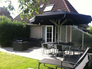 埃尔讷沃德Lush holiday home in Earnew ld的庭院配有桌椅和遮阳伞。