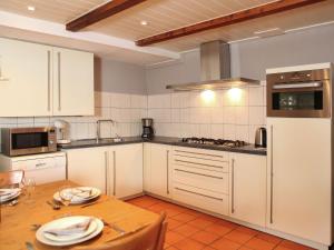 莱尔丹Quaint Farmhouse near River in Oosterwijk的厨房配有白色橱柜和木桌