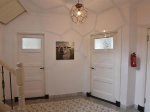 斯容代克Spacious Farmhouse in IJzendijke with Garden的一条走廊,有两扇白色的门和一幅狗的照片