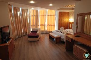 得土安伊尔雅库塔酒店的酒店客房配有一张床、一把椅子和一台电视。