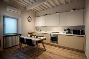 波吉奥的圣多纳托old medieval apartment的厨房配有桌子和墙上的时钟