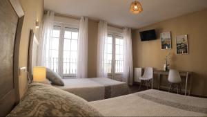 卡里翁德洛斯孔德斯Hostal Santiago的一间卧室配有两张床、一张桌子和两个窗户。