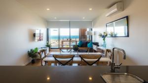 Werribee SouthWaterfront Apartments Marinaquays -Apt 221 and Apt 234的用餐室以及带桌椅的起居室。