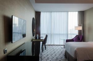 泗水Hotel Ciputra World Surabaya managed by Swiss-Belhotel International的酒店客房配有一张床和一张书桌及一台电视