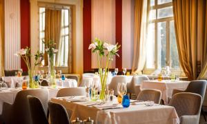 奥帕提亚Heritage Hotel Imperial - Liburnia的一间设有白色桌椅和鲜花的餐厅