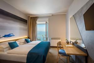 奥帕提亚Hotel Istra - Liburnia的酒店客房设有一张床和一张书桌,享有美景。