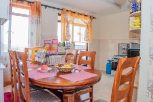 内罗毕JKIA homestays的厨房配有带椅子的木桌和桌子。