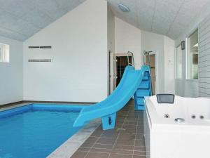 格莱斯堡20 person holiday home in Glesborg的一座房子里一个带蓝色滑梯的游泳池