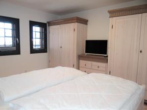 巴特Speicher Residenz Barth E4 App 9的卧室配有白色的床和平面电视。